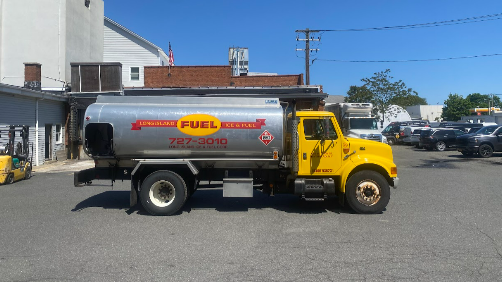 A photo of a yellow, silver, and red oil truck sitting in a parking lot on a sunny day