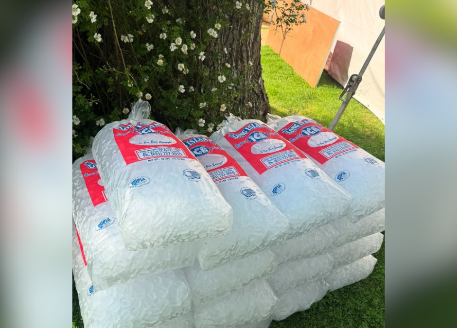 Bags of pre-packaged ice on a lush green lawn.