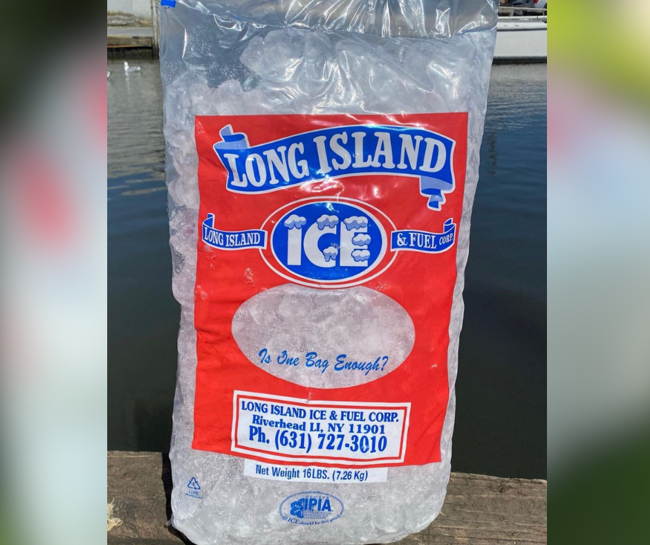A bag of pre-packaged ice sitting on a dock in front of the water.